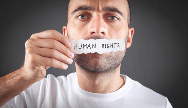 istock Man showing Human Rights text on torn paper. 1384828238
