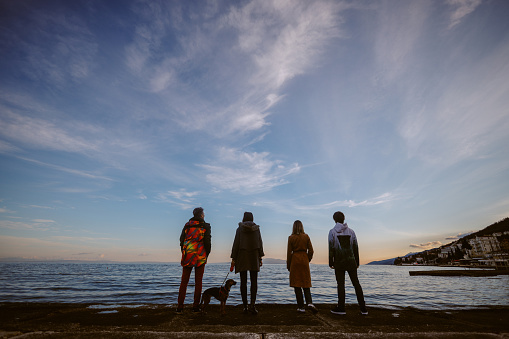 Group of friends relaxing by the Adriatic Sea in Rijeka, Croatia, with their small pet dog.