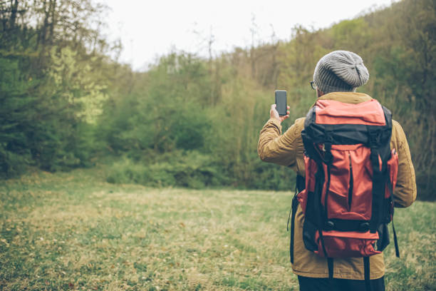 istock Man makes a photo on a smartphone in the forest 1384831025