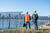 2人のアジア人男性エンジニアが機器を点検し、海辺の太陽光発電所でコミュニケーションをとった