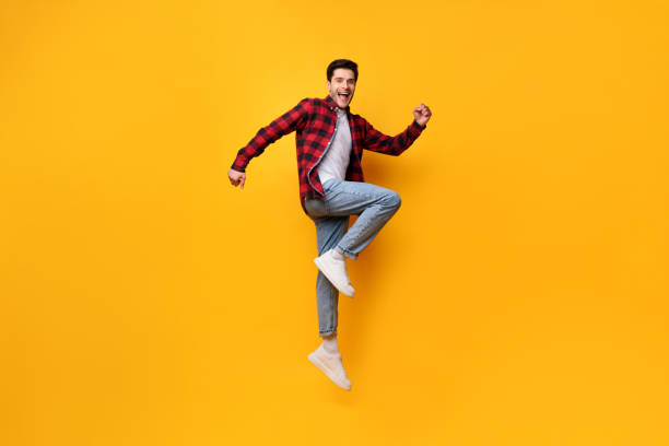 istock Excited young man jumping up at orange studio 1384840455