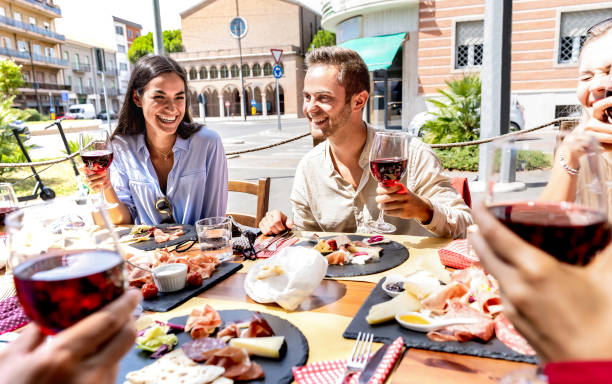 amici milienali che si divertono a bere e tostare vino rosso alla festa di pranzo in una giornata di sole - i giovani mangiano insieme cibo locale nella cantina del ristorante - concetto di stile di vita da pranzo su filtro caldo luminoso - rimini foto e immagini stock