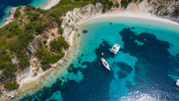 Beautiful beaches and coast of Ionian island Amazing coast with beautiful beach and forest around on Ionian sea and anchored sailboat in bay. Ithaca island, Gidaki bay and beach, Greece catamaran sailing boats stock pictures, royalty-free photos & images