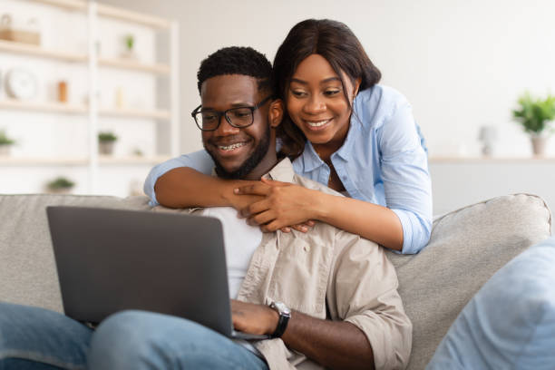 istock African american couple sitting on sofa, using laptop 1384850880