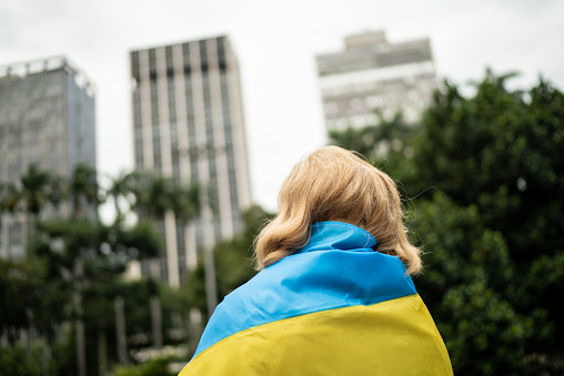 Senior woman wearing ukranian flag and contemplating outdoors