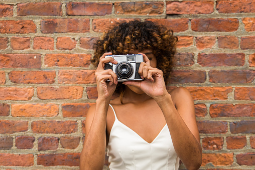 Afro-american woman portrait on a brick wall, playful and beautiful female with positive mood