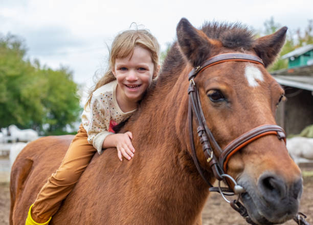 счастливая маленькая девочка верхом на коне пони босиком и смеется - bareback стоковые фото и изображения