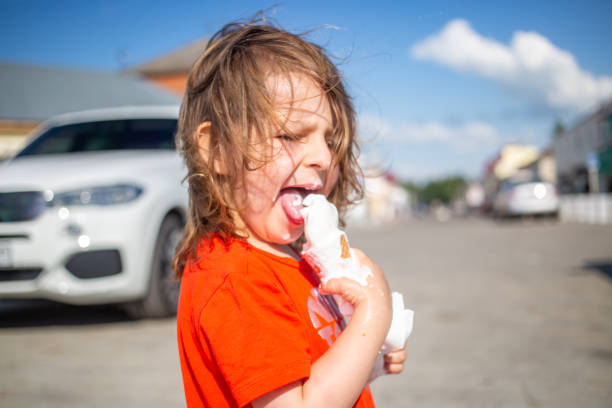 istock Cheerful child licking a vanilla ice cream on the beach 1384858543