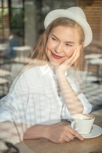 istock Beautiful woman drinking coffee and having a good time in cafe 1384860254