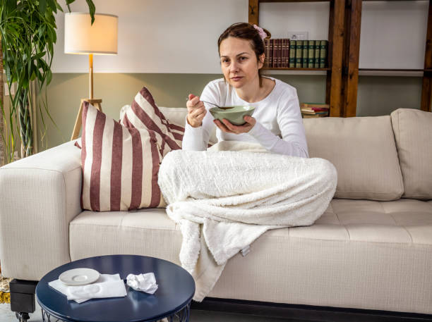 istock Woman eating soup on a sofa bed 1384863335