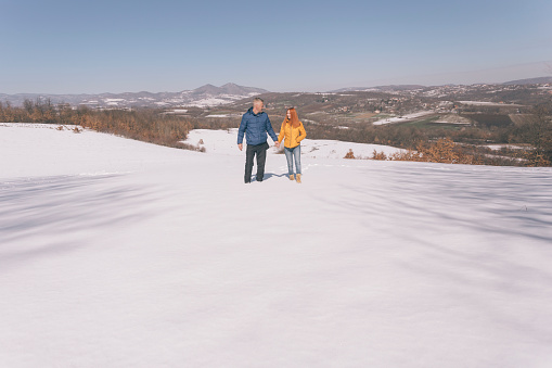 Couple in love walking and having fun outdoors in snow on sunny winter day
