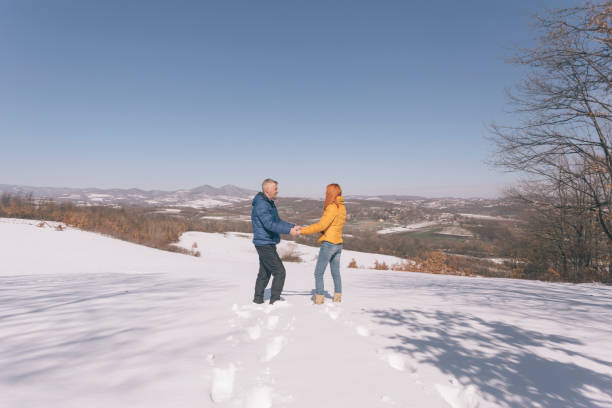 Young Asian couple holding hands walking together during travel Ouchi-juku village in Fukushima prefecture covered in snow. Man and woman enjoy outdoor lifestyle travel Japan on winter holiday vacation.