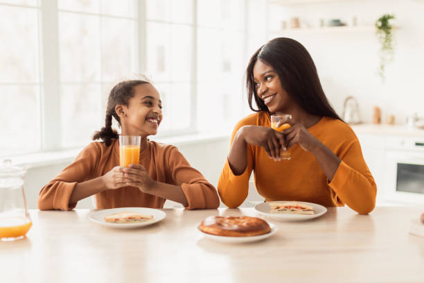 istock African Mommy And Daughter Having Lunch Drinking Juice In Kitchen 1384867341