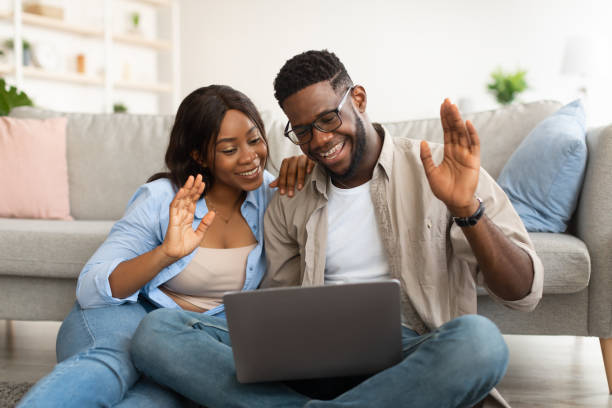 istock Black couple having videocall using laptop waving hands 1384869686