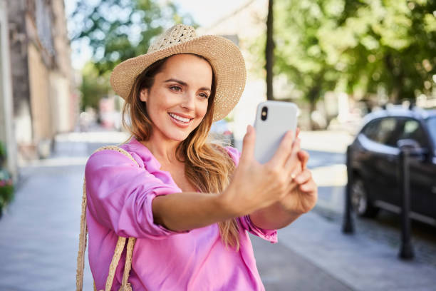 istock Stylish woman taking selfie while walking on street 1384870912