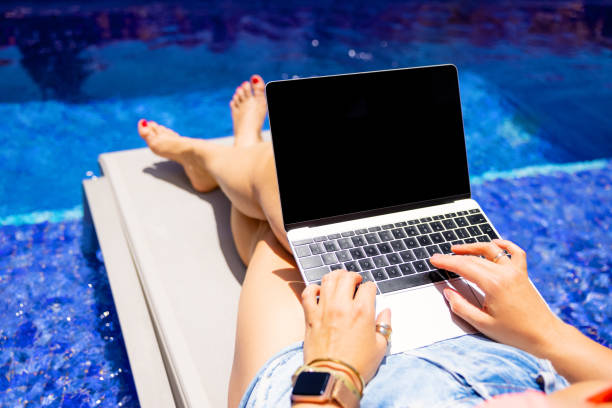 istock Female using laptop on vacation by the pool 1384871661