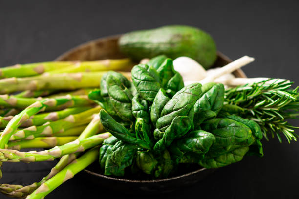 istock Various green vegetables on a dark background. Asparagus, spinach, avocado, garlic. Vegetarian food concept. 1384871963