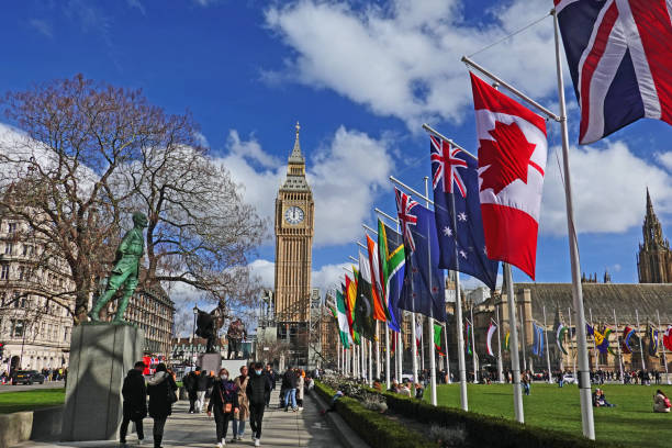 looking at big ben from parliament square with commonwealth flags flying against a bright blue sky - british empire imagens e fotografias de stock