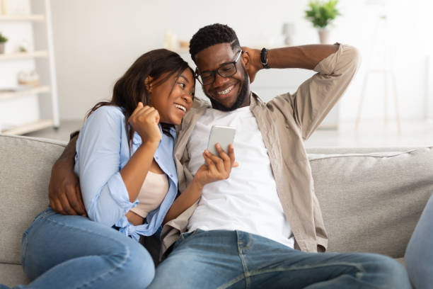 istock African american couple sitting on couch, using cellphone 1384874855