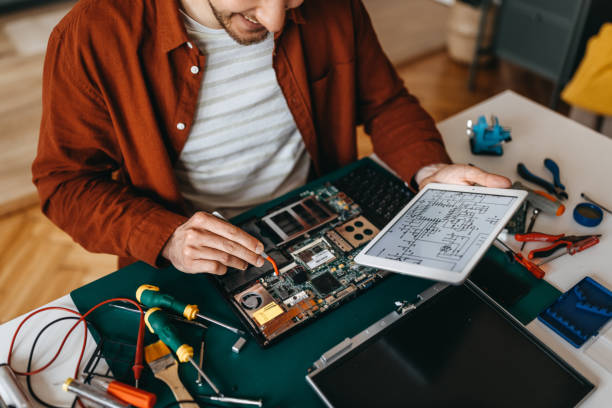 istock Young man with digital tablet repairing laptop at home 1384877691