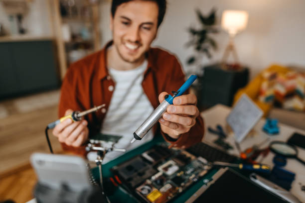 istock Young man vlogging while repairing laptop at home 1384878882
