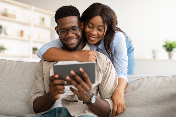 istock African american couple sitting on sofa, using tablet 1384878982