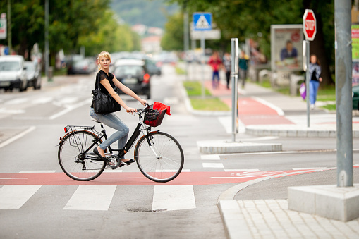 Young Woman Crossing the Street on Bicycle.