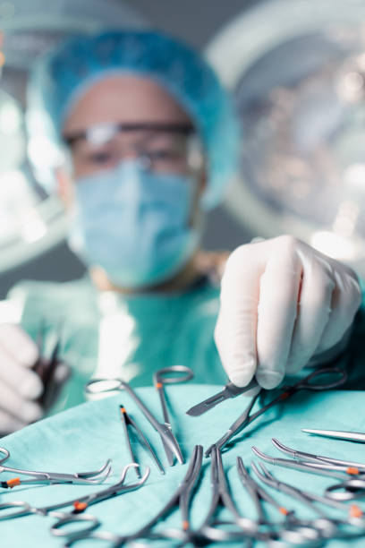 Surgeon reaching for scalpel blade during surgery stock photo