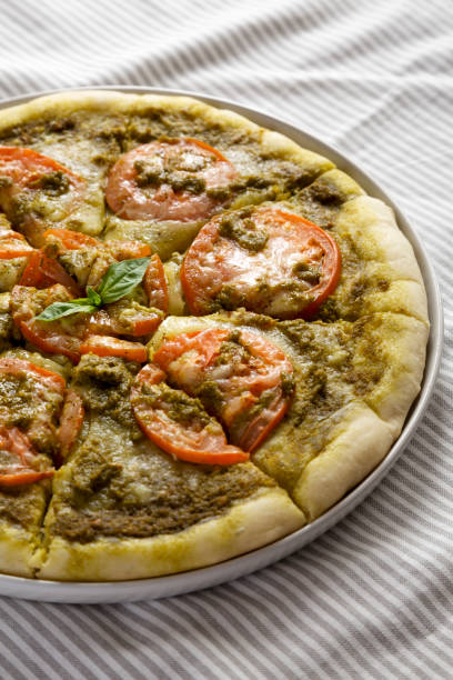 istock Homemade Pesto Pizza with Fresh Tomatoes and Mozzarella on cloth, low angle view. 1384881202