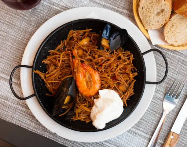 Photo of Spanish seafood fideua, noodle paella with aioli