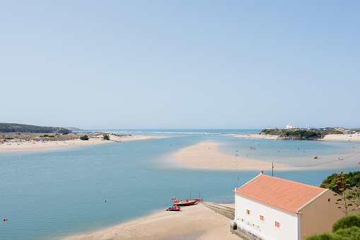 Beautiful aerial view of Alentejo coast. River arriving to the sea and beach. unrecognizable people practicing water sports on the beach. Portugal, Europe