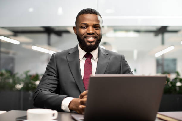 istock Handsome black businessman posing at workdesk in office 1384889316