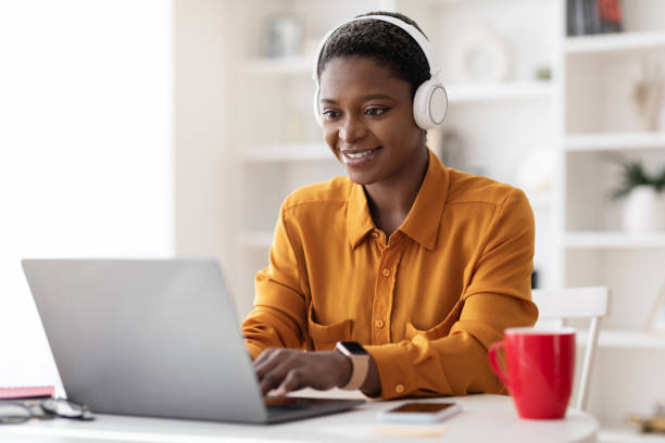 atrakcyjna czarna kobieta uczestnicząca w webinarium, korzystająca z laptopa i zestawu słuchawkowego - building contractor audio zdjęcia i obrazy z banku zdjęć