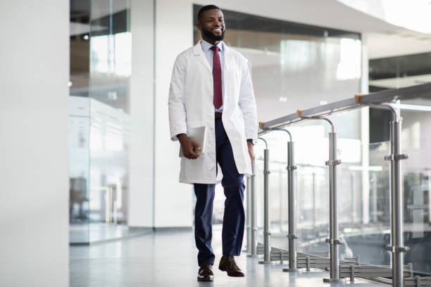 joyeux scientifique noir marchant devant le laboratoire, tenant une tablette numérique - scientist male young adult doctor photos et images de collection