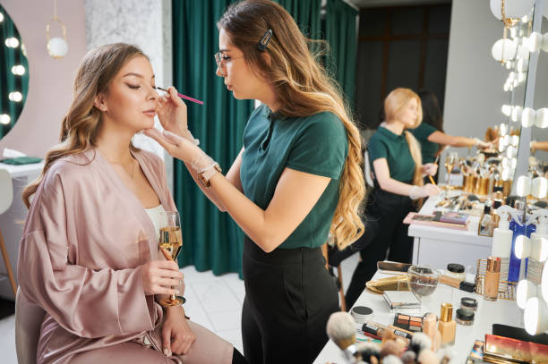 istock Woman makeup artist applying eyeshadow on client eyelid. 1384890670