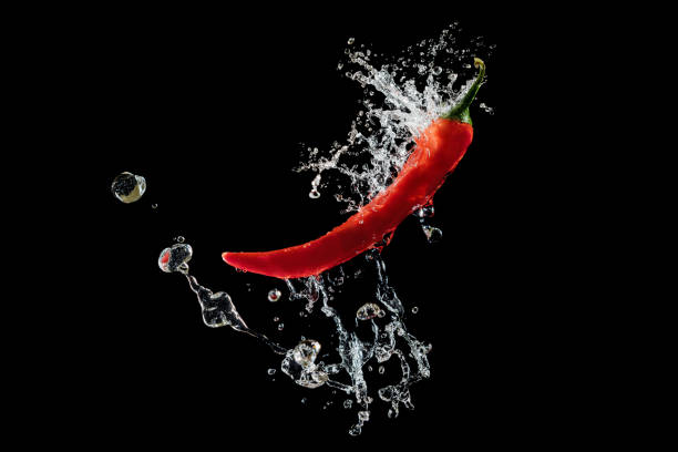 istock Red pepper with water splash over black background 1384891007