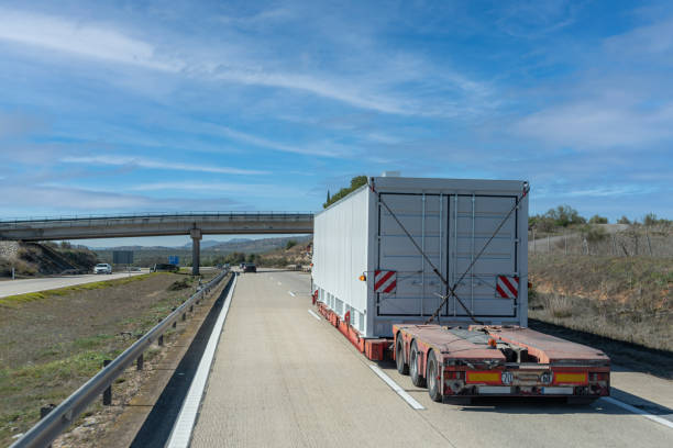 istock Platform truck loaded with a huge container that, due to its size, is marked as special transport. 1384891060