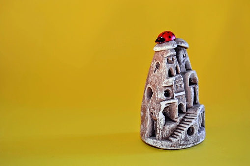 Miniature fairy chimneys and ladyclock (coccinellidae) stays top of the fairy chimneys Isolated yellow background.