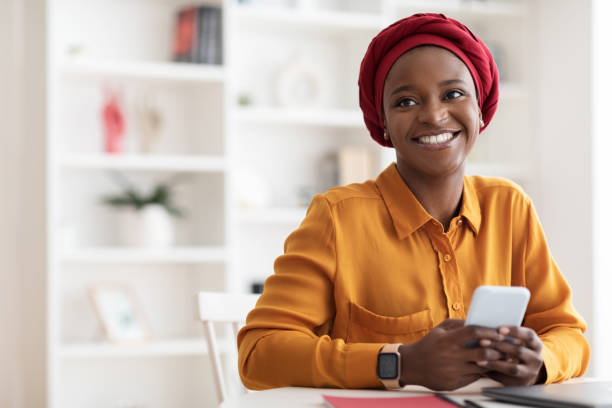 istock Positive muslim black woman using mobile phone and smiling 1384891857