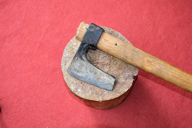 An axe stays on a piece wood with red carpet background.