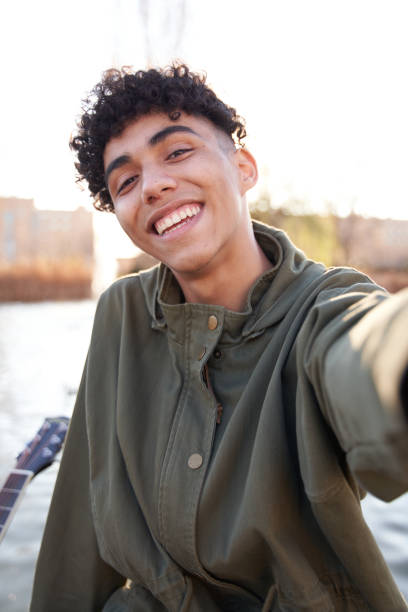 joven adolescente tomando una selfie con un teléfono inteligente en un parque de la ciudad - photography teenagers only vertical teenager fotografías e imágenes de stock