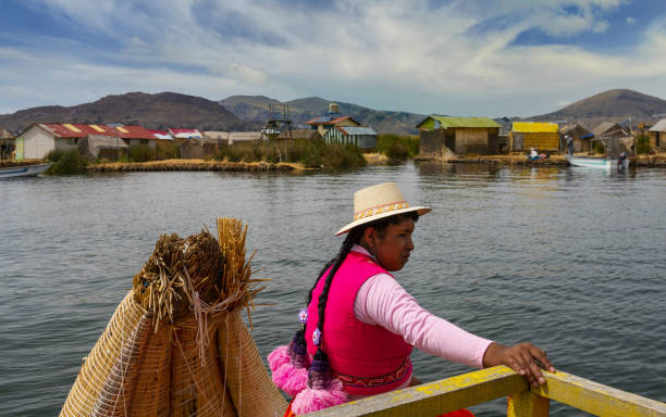 Puno, Peru, November 17, 2021: A woman of the indigenous Uros ethnic group living on floating islands on the Titicaca Lake. The islands are made of reeds and require constant repairs. Likewise, their boats are made of reeds.