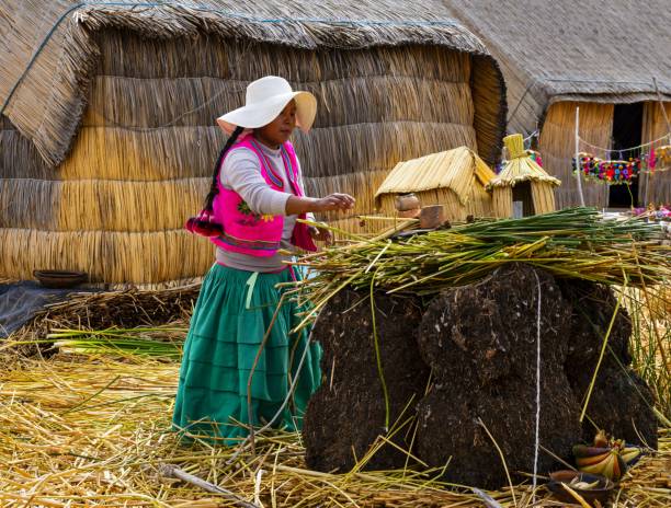 Puno, Peru, November 17, 2021: A young woman of the indigenous Uros ethnic group living on floating islands on the Titicaca Lake. The islands are made of reeds and require constant repairs. Likewise, their boats are made of reeds.