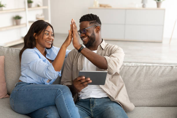 istock African american couple using tablet, celebrating win giving high five 1384894897