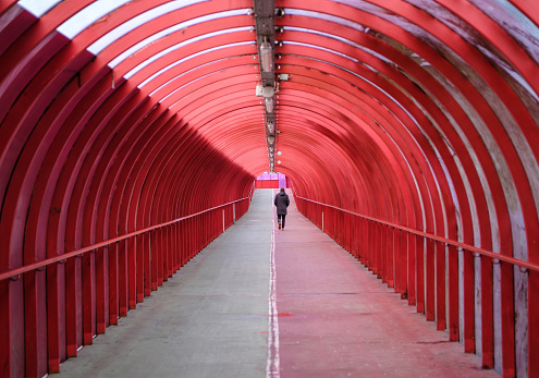A Man Walking Alone Through A Covered Walkway At An Airport Or Train Station