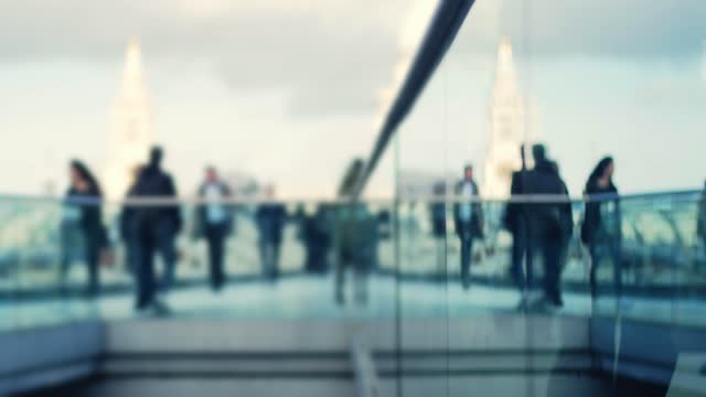Business people rush hour walking through a glass and metal bridge
