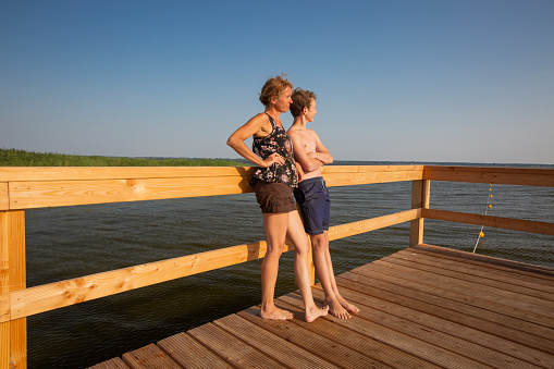 Happy mother and son are standing on a pier - looking sideways - Mecklenburg Vorpommern, Germany - copy space