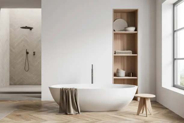 Light bathroom interior with shower and white bathtub on hardwood floor. Bathing accessories on shelf in wall, window on countryside. Copy space empty white wall, 3D rendering