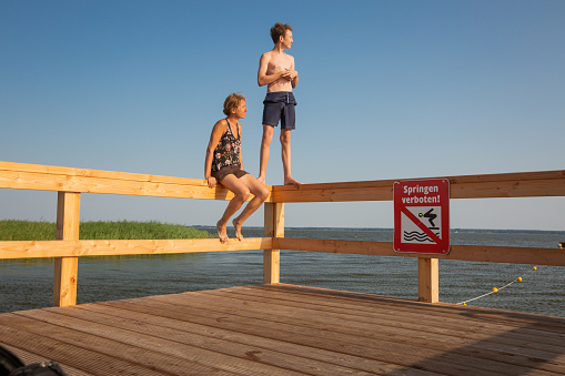 Happy mother and son are on the parapet of a pier with the sign - don’t jump
