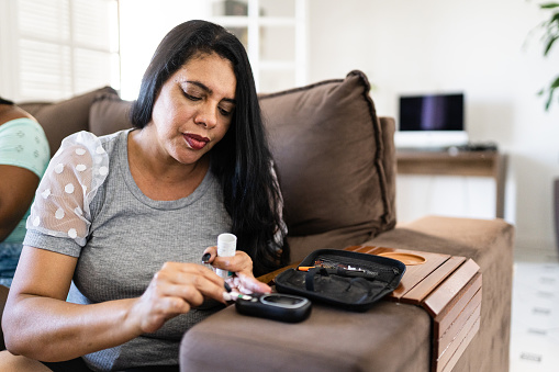 Mujer que controla el nivel de azúcar en la sangre en casa photo